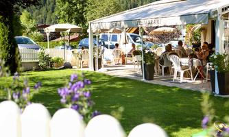 A cozy restaurant with outdoor seating and sun umbrellas. Guests enjoy their time in the well-maintained garden.