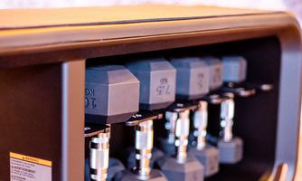 A modern dumbbell set in a storage cabinet. The dumbbells are arranged in various weights.