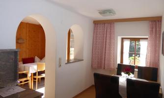 A cozy dining area with a table group and a window. The walls are painted light and there are wooden details.
