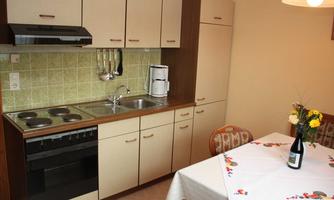 A cozy kitchen with modern appliances and a small dining area. A vase with fresh flowers is on the table.