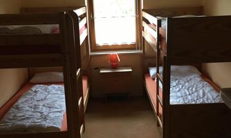 A simple bedroom with two bunk beds. The window provides ample daylight.