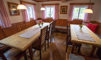 A cozy room with wooden tables and chairs. Bright windows and pink curtains create an inviting atmosphere.
