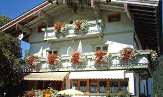 A traditional house with a beautiful balcony, adorned with colorful flowers. It looks inviting and charming in a nature-friendly environment.