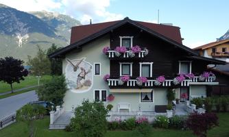 A traditional multi-story house with blooming balcony boxes. On the wall, there is a large mural depicting a historical scene.