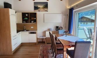 A modern kitchen with a dining table and chairs.  
Large space with wooden ceilings and plenty of natural light.