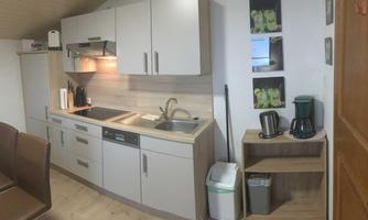 A modern kitchen with gray cabinets and a light countertop. On the countertop, there are kitchen appliances and utensils.