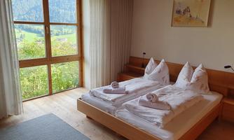A cozy bedroom with a double bed and a view of the mountains. Large windows let in plenty of natural light.