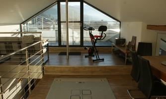 A modern rooftop gallery with a large window and a view of the mountains and the city.