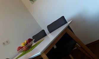 A modern dining table with black chairs and a bowl full of fruit. Pictures of fresh foods hang on the wall.