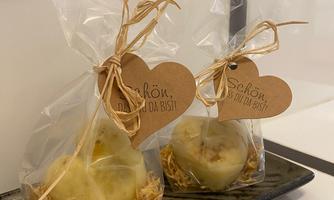 Two lovingly packaged soaps in transparent foil with a heart-shaped tag. The tag reads "Beautiful that you are here!" and the soaps are placed on a decorative plate.