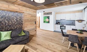 A modern, spacious apartment with hardwood floors and a cozy seating area. The bright kitchen is well equipped and has an inviting atmosphere.