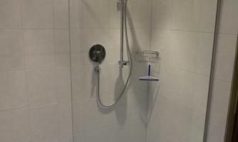 A modern shower cubicle with glass separation and bright tiles. The wall is decorated with a colored border.
