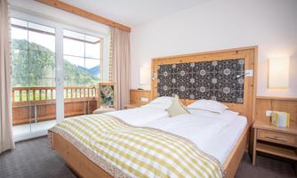 A cozy bedroom with a large double bed and a balcony. The view of the mountains creates a relaxing atmosphere.