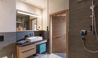 A modern bathroom with a shower and sink. It has elegant fixtures and bright colors.