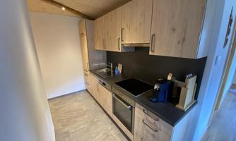 A modern kitchen with wooden cabinets and black countertops. The equipment includes a stove, a sink, and various kitchen appliances.
