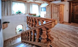 A beautiful wooden staircase in a cozy interior. Large windows let in plenty of daylight, and the decor is warm and inviting.