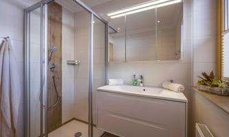 A modern bathroom with a shower and a sink. The walls are light, and the space feels friendly and inviting.