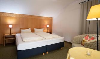 A cozy bedroom with a double bed and two nightstands. A comfortable armchair and a small table complete the relaxing atmosphere.