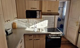 The kitchen is designed modernly with bright wooden cabinets and an elegant countertop. It features a stove, a sink, and modern kitchen appliances.