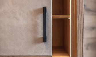 A modern piece of furniture made of wood and stone with a black handle. The drawer has several compartments and is elegantly designed.