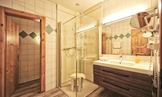 A modern bathroom with a glass shower and a stylish bathtub. The walls are tiled in light colors, and there is a wood finish that exudes coziness.