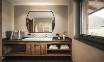 A modern bathroom with a stylish sink and large mirror. Natural materials and a beautiful view through the window create a relaxed atmosphere.