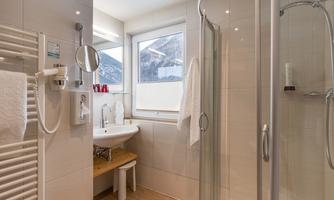 A modern bathroom with a shower and a large window. Bright tiles and wooden details create an inviting atmosphere.