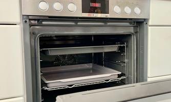 A modern oven with the door open. Inside, two baking trays can be seen.