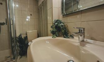 A modern bathroom with a shower and a sink. The walls are in gentle beige and cream tones.