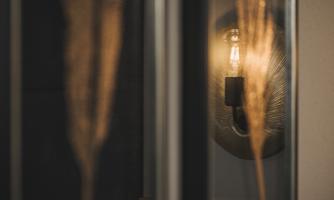 A stylish wall lamp softly illuminates behind a curtain. The atmosphere is warm and inviting.