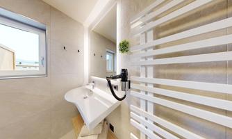 A modern bathroom with an elegant sink and a large window. The walls are bright and equipped with white wall radiators.