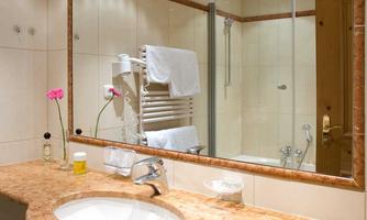 An elegant bathroom with a sink and a large mirror. Towels and decorative elements create an inviting atmosphere.