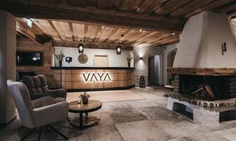 A stylish hotel lobby with wooden ceilings and a cozy fireplace. The reception area is designed to be modern and inviting.