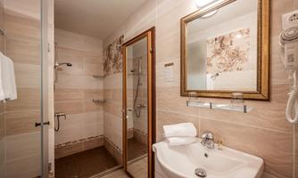 A modern bathroom with a shower and a sink. The walls are brightly tiled and adorned with floral decor.