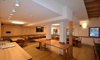 A modern restaurant with wooden decor and bright walls. There are tables and chairs set up for guests.