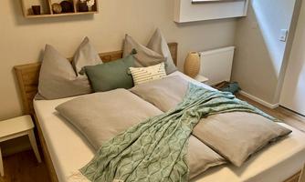 A cozy bedroom with a double bed, padded pillows, and a blanket. A warm and inviting atmosphere.