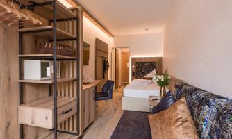 A modern room with two beds, a table, and stylish decor. A plant adds a fresh touch to the space.
