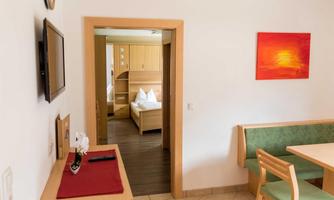 A cozy interior with an open door to a bedroom. A picture hangs on the wall and there is a dining area with a table and chairs.