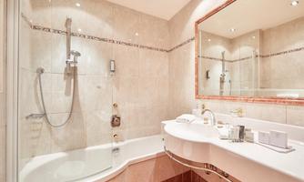 A modern bathroom with a shower and a bathtub. The walls are brightly tiled and there is a large mirror.