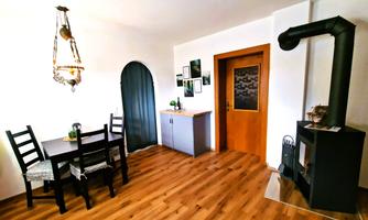 A cozy dining area with a wooden table and chairs. The wall is painted light, and there is a fireplace in the corner.