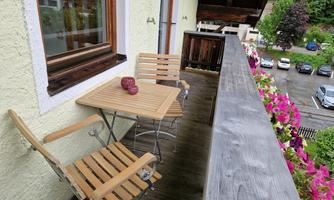 South balcony with a table and two chairs made of acacia wood, the balcony flowers enhance the view.