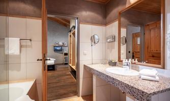 A modern bathroom with a granite sink and a bathtub. The space is bright and inviting, with a mirror and hygiene products.