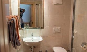 A modern bathroom with a shower, sink, and toilet. Towels and toiletries are clearly visible.