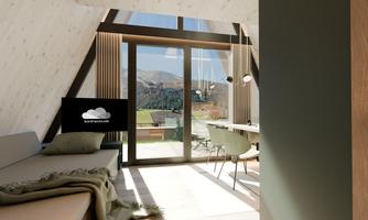 A modern room with large windows and a view of the mountains. The decor is simple and inviting, featuring a cozy sofa and a dining table.
