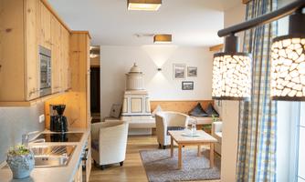 A bright and modern kitchen with wooden furniture and a cozy living area. The space is friendly and inviting, ideal for relaxation.