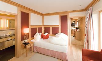 A cozy room with a double bed and rustic wood design. The warm color scheme and natural light create an inviting atmosphere.