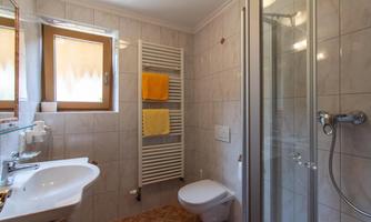 A modern bathroom with a white sink and shower. Subtle tiles and yellow towels create a pleasant atmosphere.