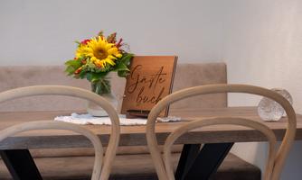 A beautiful table with two chairs and a bouquet of sunflowers. In the background, there is a guestbook.