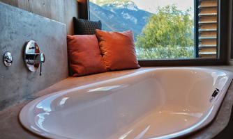 A modern bathtub with a view of the mountains. Soft cushions add a welcoming atmosphere to the space.