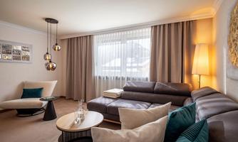 A modern living room with a comfortable sofa and a stylish armchair. Large windows let in plenty of light and create an inviting atmosphere.